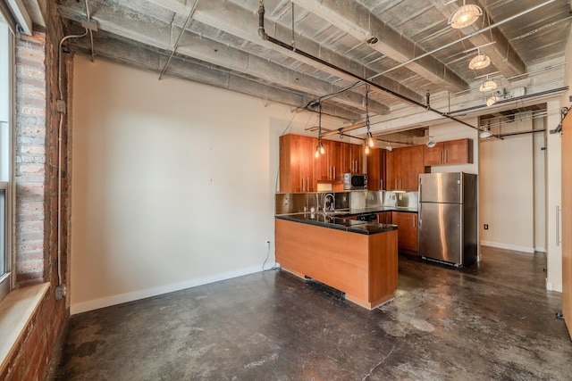 112 11th St Unit 506, Des Moines, IA 50309 - kitchen with appliances with stainless steel finishes, brown cabinetry, a peninsula, concrete floors, and dark countertops