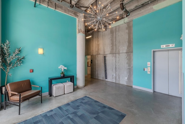 112 11th St Unit 506, Des Moines, IA 50309 - misc room with finished concrete flooring, a towering ceiling, elevator, and a chandelier
