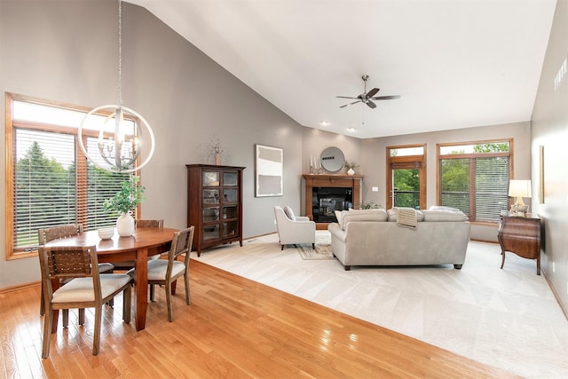 3605 151st St, Urbandale, IA 50323 - dining space featuring a chandelier, light wood finished floors, a glass covered fireplace, ceiling fan, and healthy amount of natural light