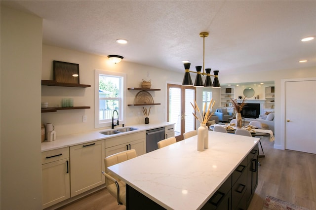 712 63rd St, West Des Moines, IA 50266 - kitchen with stainless steel dishwasher, a sink, open shelves, a center island, and light wood-style flooring