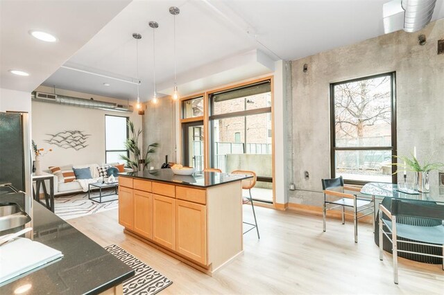 119 4th St Unit 102, Des Moines, IA 50309 - kitchen with healthy amount of natural light, light wood-style floors, light brown cabinets, and hanging light fixtures