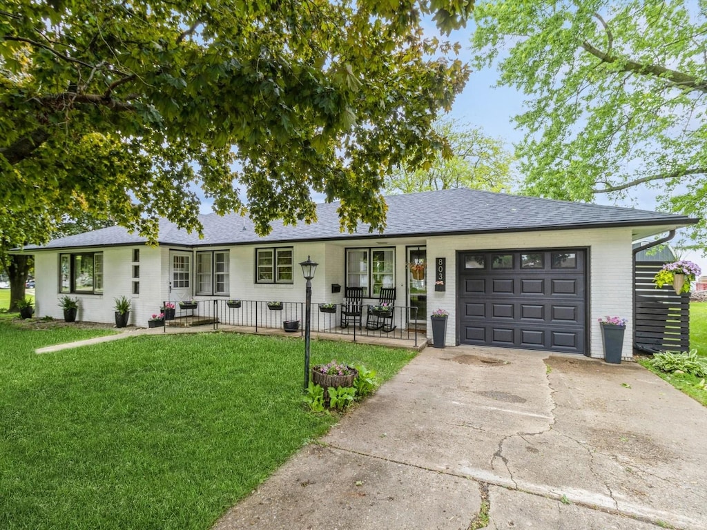 803 2nd St, Sully, IA 50251 - single story home with covered porch, an attached garage, a front lawn, concrete driveway, and a shingled roof