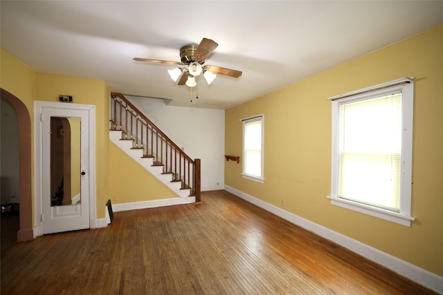 109 Greene St, Boone, IA 50036 - unfurnished living room with wood finished floors, ceiling fan, stairway, baseboards, and arched walkways