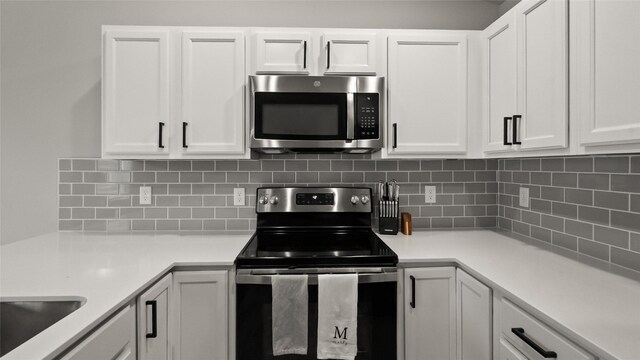812 Juniper St NW, Bondurant, IA 50035 - kitchen with stainless steel appliances, white cabinetry, light countertops, and decorative backsplash