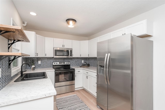406 SE Trilein Dr, Ankeny, IA 50021 - kitchen featuring appliances with stainless steel finishes, a sink, light countertops, light wood finished floors, and decorative backsplash