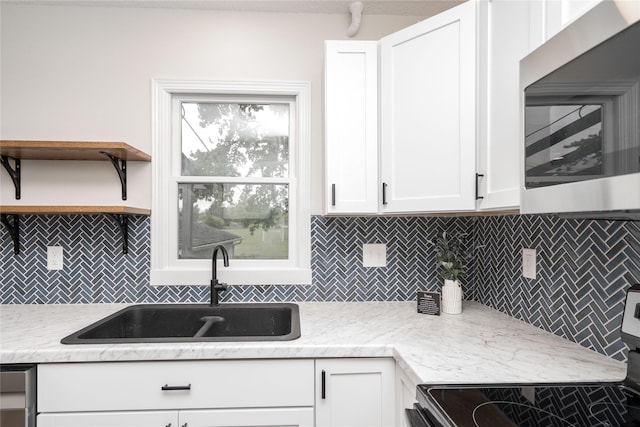 406 SE Trilein Dr, Ankeny, IA 50021 - kitchen featuring stainless steel microwave, stove, a sink, tasteful backsplash, and white cabinetry