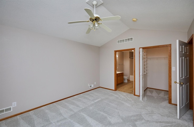 6200 Ep True Pkwy Unit 601, West Des Moines, IA 50266 - unfurnished bedroom featuring a walk in closet, lofted ceiling, light colored carpet, baseboards, and ensuite bathroom
