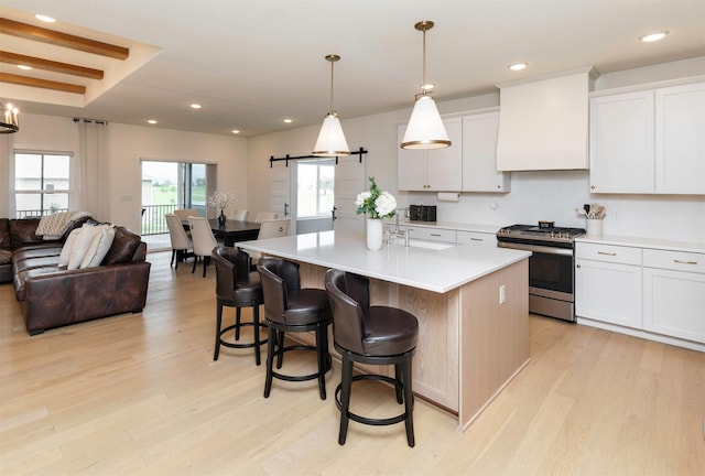 5018 NE Seneca Dr, Ankeny, IA 50021 - kitchen with gas stove, light wood-style floors, open floor plan, a barn door, and light countertops
