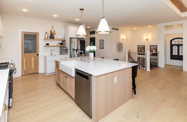5018 NE Seneca Dr, Ankeny, IA 50021 - kitchen featuring appliances with stainless steel finishes, a sink, light wood finished floors, open shelves, and a kitchen bar