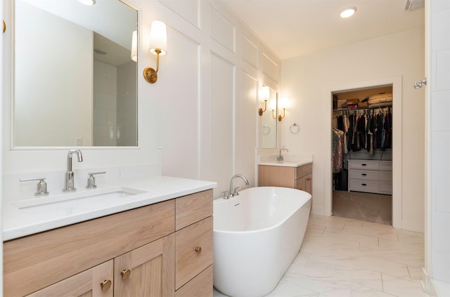 5018 NE Seneca Dr, Ankeny, IA 50021 - bathroom with marble look tiles, a freestanding tub, a walk in closet, two vanities, and recessed lighting