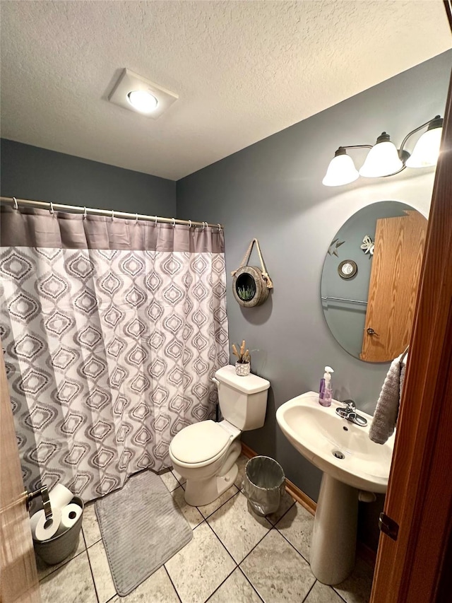 902 W Filmore St, Winterset, IA 50273 - bathroom featuring toilet, tile patterned flooring, a textured ceiling, and a shower with shower curtain
