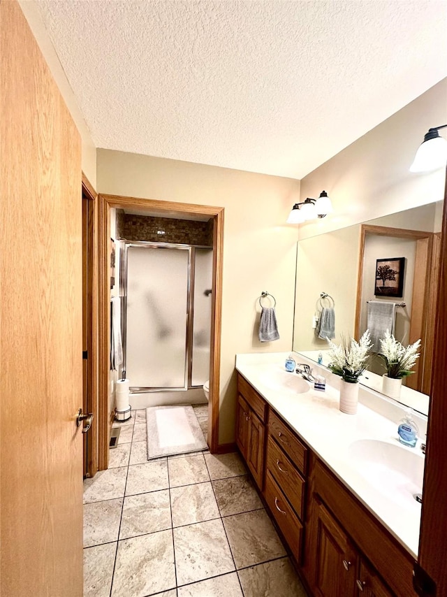 902 W Filmore St, Winterset, IA 50273 - full bath with double vanity, a textured ceiling, a shower stall, and toilet