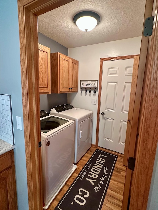 902 W Filmore St, Winterset, IA 50273 - laundry area featuring independent washer and dryer, cabinet space, light wood-style flooring, and a textured ceiling