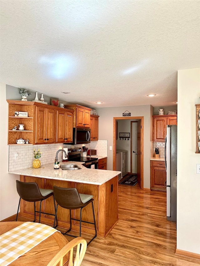 902 W Filmore St, Winterset, IA 50273 - kitchen featuring appliances with stainless steel finishes, a sink, a peninsula, backsplash, and a kitchen breakfast bar