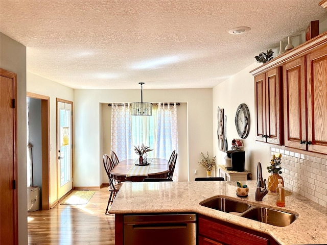 902 W Filmore St, Winterset, IA 50273 - kitchen featuring a sink, dishwasher, light wood-style flooring, a peninsula, and decorative backsplash