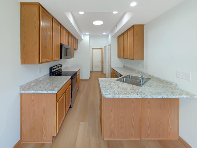 2101 Meadow Ct Unit 1304, Des Moines, IA 50320 - kitchen featuring appliances with stainless steel finishes, a sink, light wood-style floors, a peninsula, and light stone counters