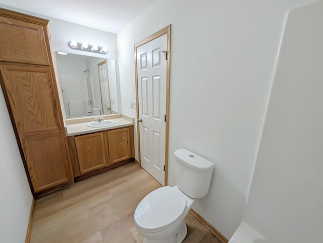 2101 Meadow Ct Unit 1304, Des Moines, IA 50320 - bathroom featuring toilet, vanity, wood finished floors, a shower, and baseboards