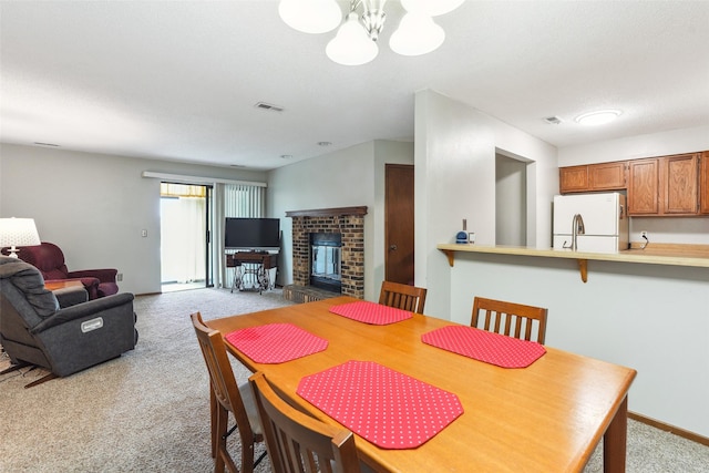 4829 86th St Unit 6, Urbandale, IA 50322 - dining space with carpet, a brick fireplace, a chandelier, and baseboards
