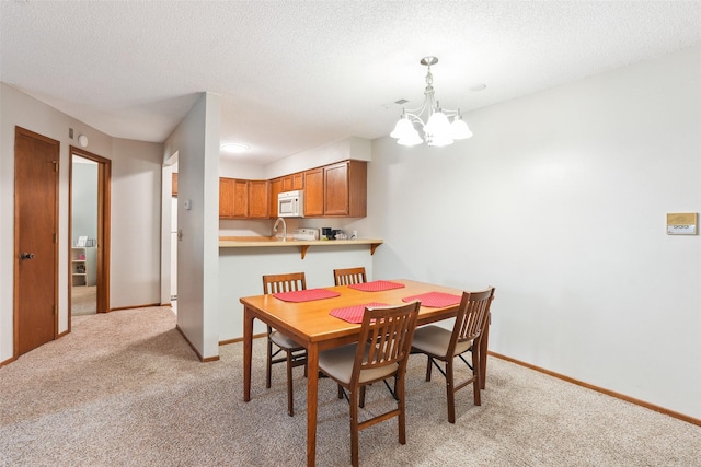 4829 86th St Unit 6, Urbandale, IA 50322 - dining area featuring light carpet, a chandelier, a textured ceiling, and baseboards