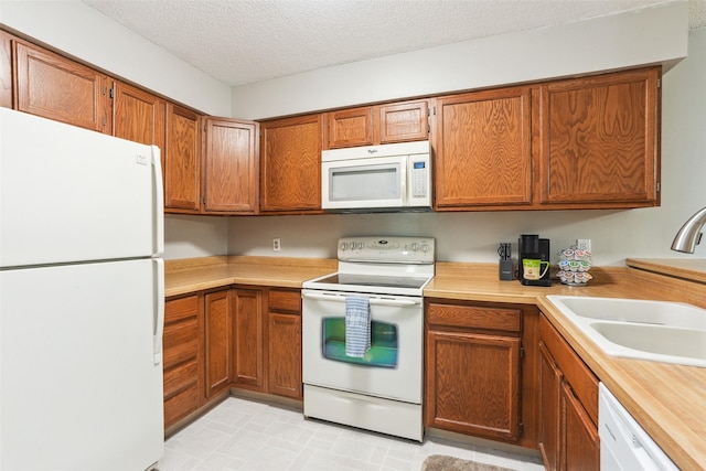4829 86th St Unit 6, Urbandale, IA 50322 - kitchen featuring white appliances, a sink, light countertops, brown cabinetry, and a textured ceiling