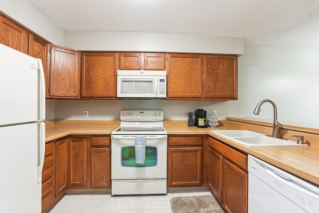 4829 86th St Unit 6, Urbandale, IA 50322 - kitchen featuring white appliances, a sink, a textured ceiling, light countertops, and brown cabinetry