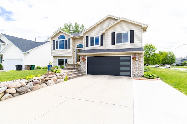 704 13th St SE, Altoona, IA 50009 - split foyer home with an attached garage, driveway, a front yard, and stone siding