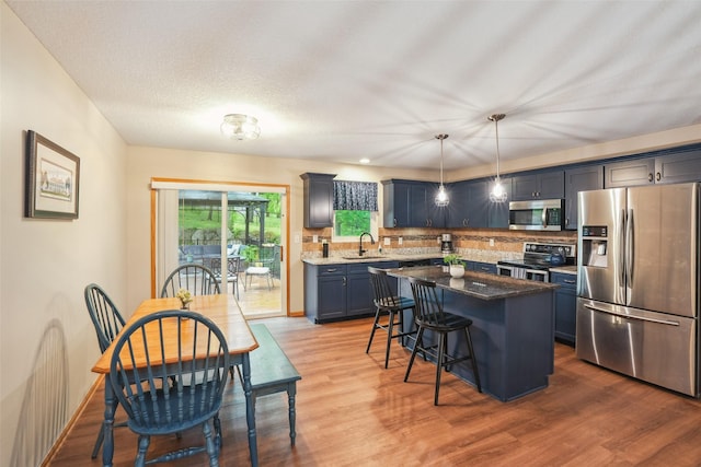 5200 Pine Valley Dr, Pleasant Hill, IA 50327 - kitchen featuring appliances with stainless steel finishes, a breakfast bar, tasteful backsplash, light wood finished floors, and a sink