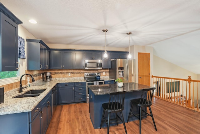 5200 Pine Valley Dr, Pleasant Hill, IA 50327 - kitchen with appliances with stainless steel finishes, a sink, wood finished floors, a kitchen bar, and lofted ceiling