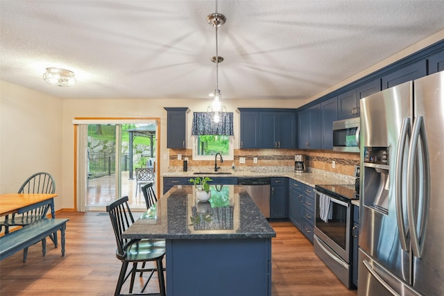 5200 Pine Valley Dr, Pleasant Hill, IA 50327 - kitchen featuring appliances with stainless steel finishes, blue cabinets, a sink, a breakfast bar, and a textured ceiling