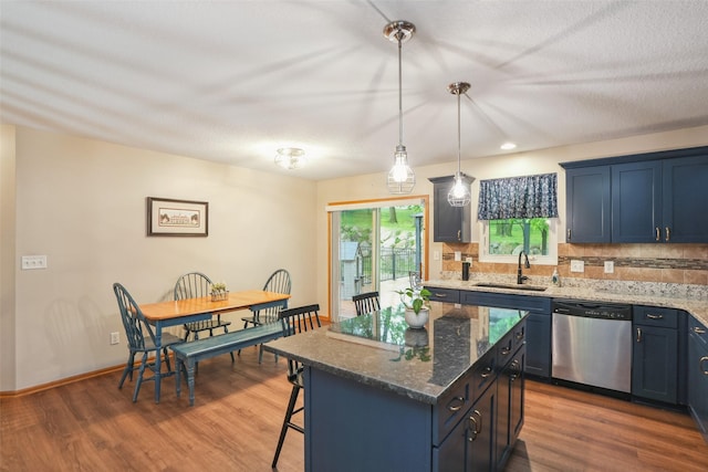 5200 Pine Valley Dr, Pleasant Hill, IA 50327 - kitchen with stainless steel dishwasher, a sink, a kitchen bar, decorative backsplash, and wood finished floors