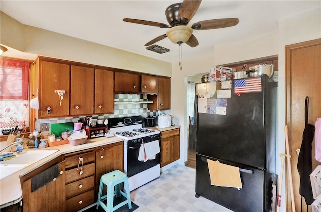 3517 50th St, Des Moines, IA 50310 - kitchen with freestanding refrigerator, range with gas stovetop, brown cabinetry, ceiling fan, and a sink