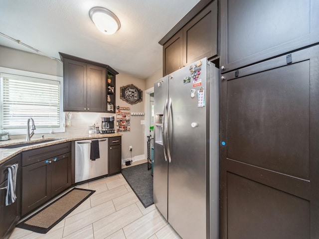 4022 Clinton Ave, Des Moines, IA 50310 - kitchen with stainless steel appliances, a sink, light stone countertops, and dark brown cabinetry
