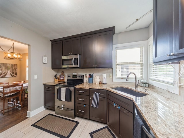 4022 Clinton Ave, Des Moines, IA 50310 - kitchen featuring appliances with stainless steel finishes, a sink, a chandelier, and dark brown cabinetry