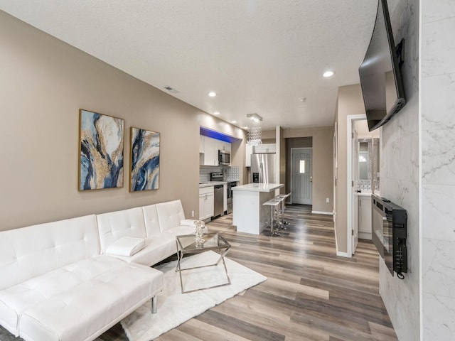 2917 2nd Ave, Des Moines, IA 50313 - living room with light wood finished floors, heating unit, recessed lighting, a textured ceiling, and baseboards
