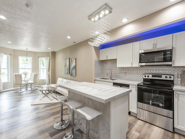 2917 2nd Ave, Des Moines, IA 50313 - kitchen with stainless steel appliances, a sink, light wood finished floors, tasteful backsplash, and recessed lighting