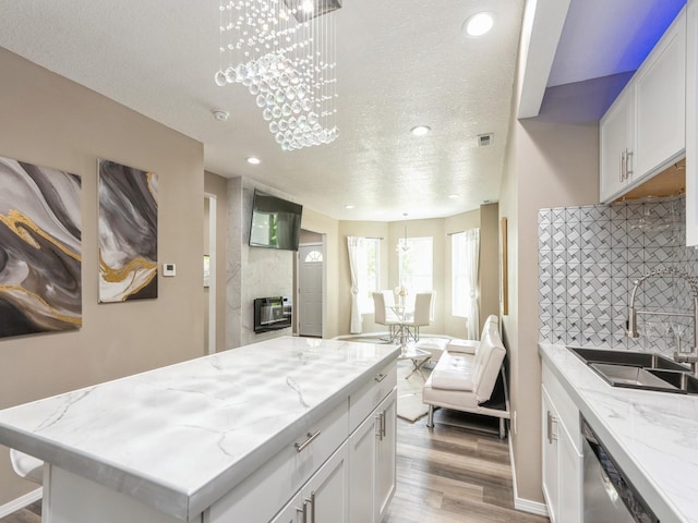 2917 2nd Ave, Des Moines, IA 50313 - kitchen with a sink, a textured ceiling, white cabinetry, decorative backsplash, and wood finished floors