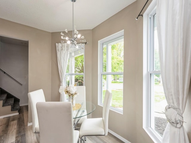 2917 2nd Ave, Des Moines, IA 50313 - dining space featuring a chandelier, baseboards, wood finished floors, and stairway