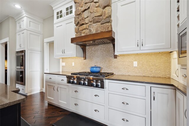 2492 55th St, Vinton, IA 52349 - kitchen featuring appliances with stainless steel finishes, custom range hood, white cabinetry, dark wood finished floors, and tasteful backsplash