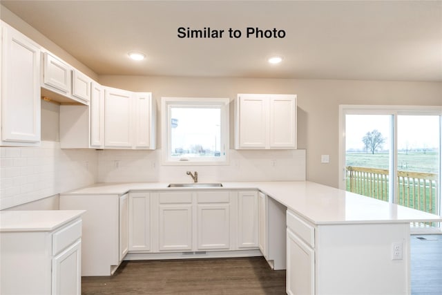 25087 Bluebird Cir, Adel, IA 50003 - kitchen with a sink, a peninsula, dark wood-style flooring, decorative backsplash, and recessed lighting