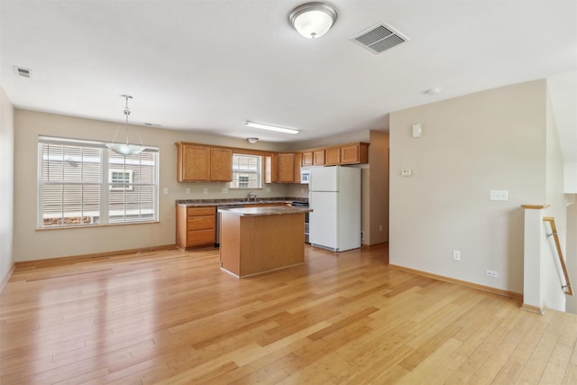 15203 Greenbelt Dr, Urbandale, IA 50323 - kitchen with freestanding refrigerator, a sink, a center island, light wood-type flooring, and baseboards