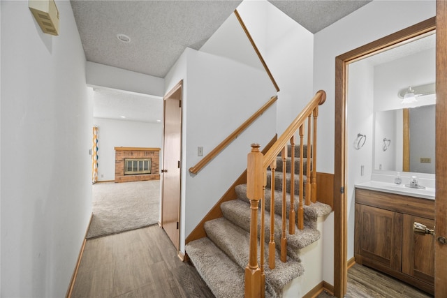 8532 Oakwood Dr, Urbandale, IA 50322 - stairs with wood finished floors, a brick fireplace, and a textured ceiling