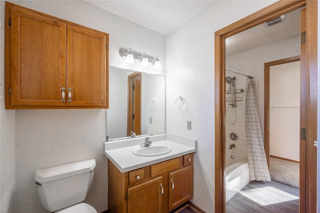 8532 Oakwood Dr, Urbandale, IA 50322 - bathroom with vanity, toilet, a textured ceiling, and shower / tub combo