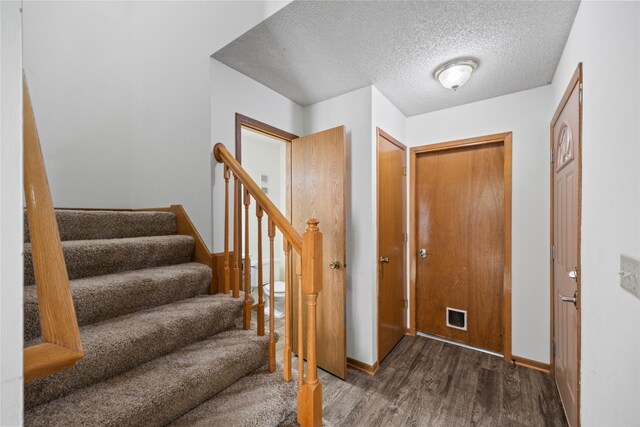 8532 Oakwood Dr, Urbandale, IA 50322 - foyer entrance featuring wood finished floors, a textured ceiling, stairs, and baseboards