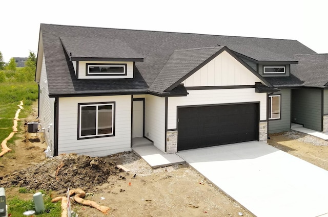 2502 NE 6th St, Grimes, IA 50111 - view of front of property featuring an attached garage, driveway, roof with shingles, stone siding, and board and batten siding