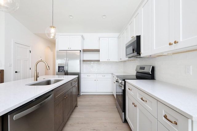 2500 NE 6th St, Grimes, IA 50111 - kitchen featuring appliances with stainless steel finishes, a sink, open shelves, light countertops, and pendant lighting