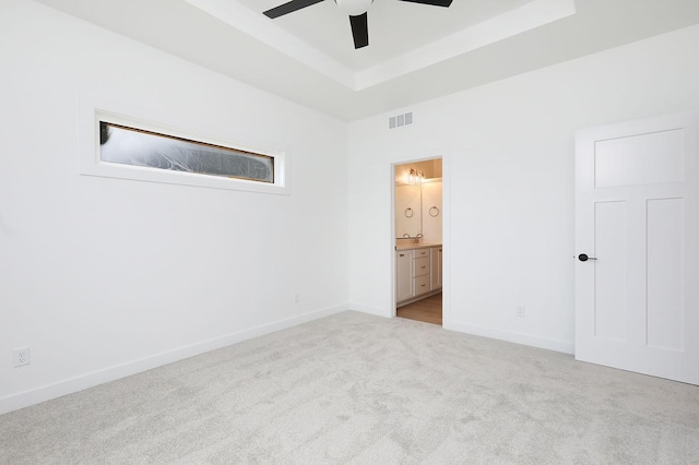 2500 NE 6th St, Grimes, IA 50111 - unfurnished bedroom with a tray ceiling, carpet flooring, baseboards, ensuite bathroom, and a ceiling fan