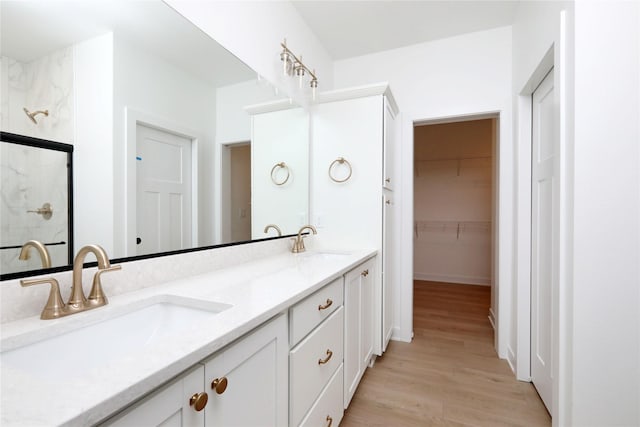2500 NE 6th St, Grimes, IA 50111 - full bath with double vanity, a shower stall, wood finished floors, and a spacious closet