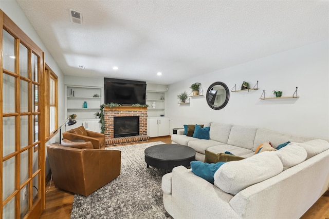 6935 NW 88th Ave, Johnston, IA 50131 - living area with wood finished floors, a brick fireplace, a textured ceiling, and recessed lighting