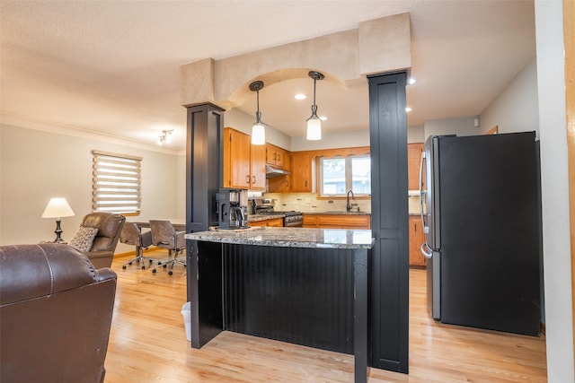 3223 Hull Ave, Des Moines, IA 50317 - kitchen with appliances with stainless steel finishes, light wood-type flooring, a peninsula, under cabinet range hood, and open floor plan