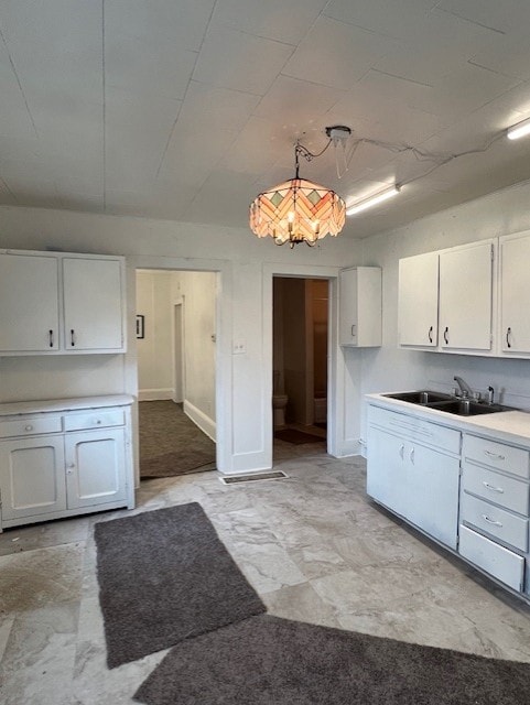 520 S Main St, Stuart, IA 50250 - kitchen featuring a sink, white cabinets, light countertops, and decorative light fixtures